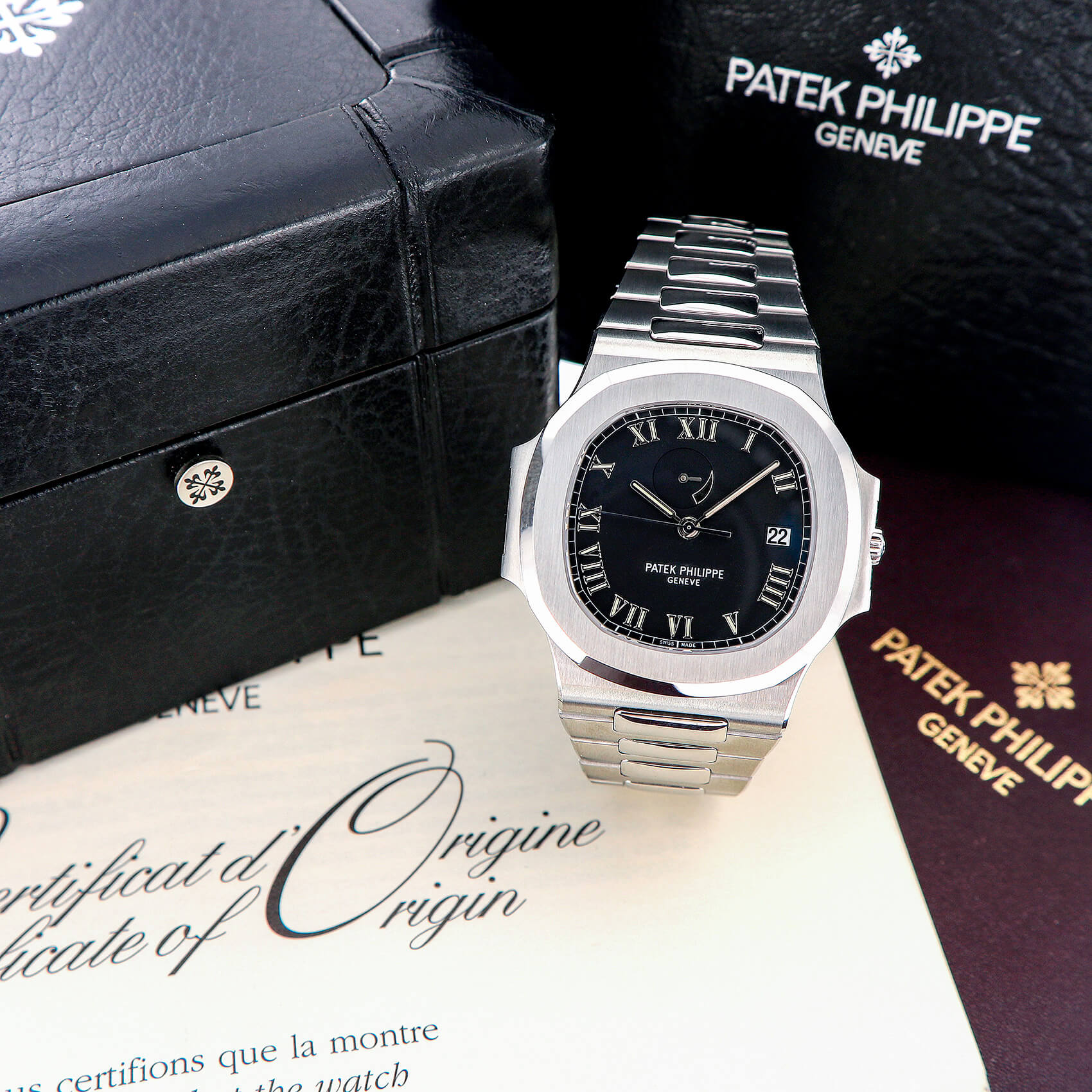 Steel sports watch with a black dial beside its box and papers